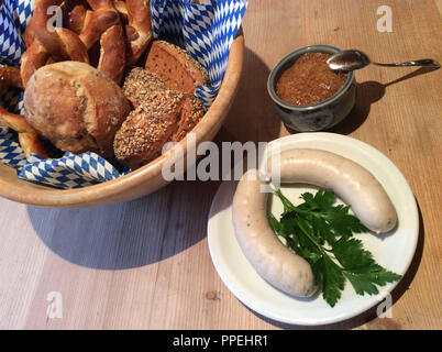 Weißwurst Snack oder Frühstück mit Brezel, Brötchen, Petersilie und Senf auf einem rustikalen Holztisch. Stockfoto