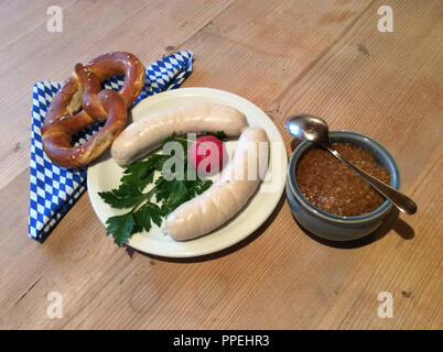 Weißwurst Snack oder Frühstück mit Brezel, Rettich, Petersilie, Senf auf einem rustikalen Holztisch. Stockfoto