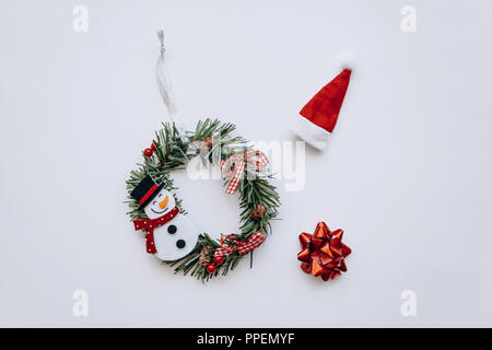 Weihnachten Kranz mit Schneemann Weihnachtsbaum Spielzeug auf weißem Hintergrund kreative festliche Idee in minimalistischem Stil. Stockfoto