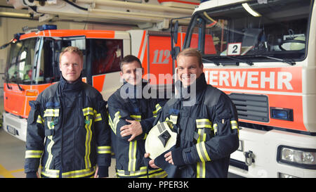 Gruppe von Feuerwehrleuten Am Einsatzfahrzeug in der Feuerwache Stockfoto