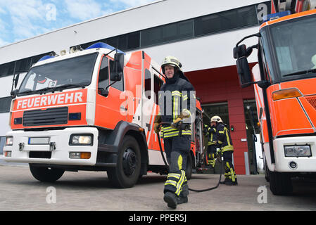 Gruppe von Feuerwehrleuten Am Einsatzfahrzeug in der Feuerwache Stockfoto