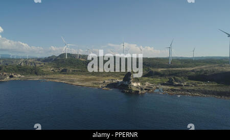 Natürliche Felsformation aus Kalkstein Stein an der Küste mit Windmühlen für elektrische Energie Produktion. Luftaufnahme von touristenattraktion Kapurpurawan Felsformation in Ilocos Norte, Philippinen, Luzon. Stockfoto