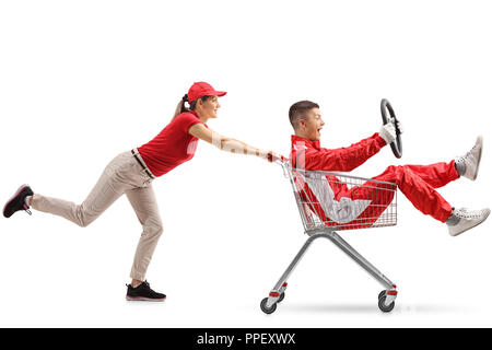 Weibliche treibt ein Warenkorb mit einem Teenager in einem Racing suit Holding ein Lenkrad auf weißem Hintergrund Stockfoto