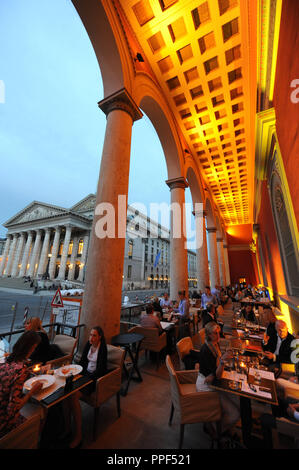 Gäste können auf der Terrasse des Restaurants "kufflers California Kitchen" in das Gebäude der ehemaligen Residenzpost auf den Max-Joseph-Platz in München. Im Hintergrund, der Bayerischen Staatsoper. Stockfoto