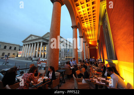 Gäste können auf der Terrasse des Restaurants "kufflers California Kitchen" in das Gebäude der ehemaligen Residenzpost auf den Max-Joseph-Platz in München. Im Hintergrund, der Bayerischen Staatsoper. Stockfoto