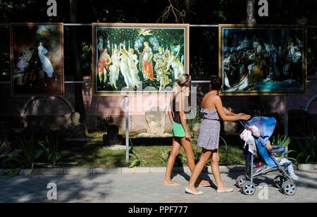 In der Ukraine. Die autonome Republik Krim. Jewpatorija. Frauen mit einem Kinderwagen spazieren auf einer Straße weiter zu einer Ausstellung von Kopien berühmter Gemälde. Stockfoto