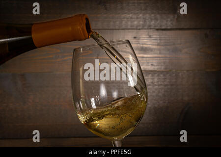 Weißwein Gießen in einem Weinglas aus einer Flasche Stockfoto