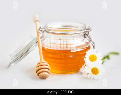 Roh Bio Honig in einem Glas mit Pendelarm und Blumen, gesunde natürliche Süßungsmittel Stockfoto