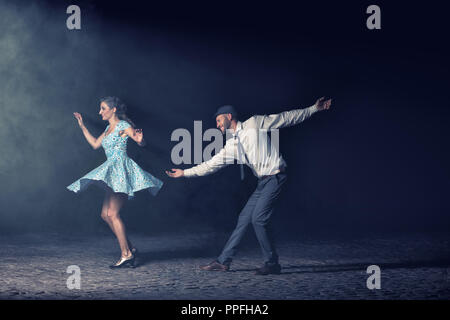 Paar tanzen Lindy Hop in der Nacht vor einem Scheinwerfer. Stockfoto