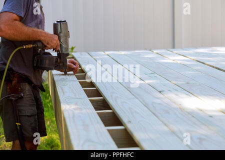 Gebäude mit Hinterhof deck mit Arbeiter setzen mit bolzenschußgeräten Deck boards Terrasse Terrasse Bau. Stockfoto