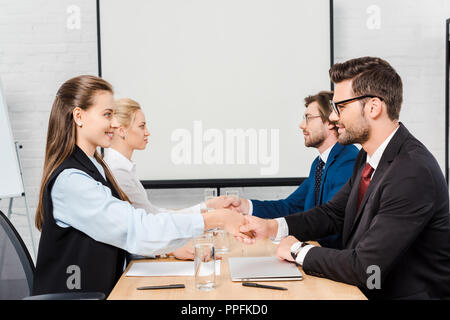 Zwei Teams von Geschäftsleuten die Hände schütteln während der Tagung in modernen Büro Stockfoto