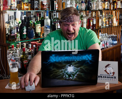 Mann im Internet Cafe sieht auf dem Laptop und schreit in Schock, Symbol Bild für das Surfen im Internet. Deutschland Stockfoto