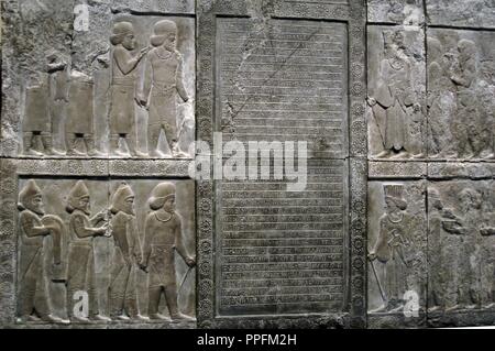 Palast von Darius I (522-486 v. Chr.). Reliefs der äußeren Wand des Treppenhauses der Apadana Darstellung In der Mitte, Keilschrift Inschrift beschreibt den Bau einer Treppe im Palast von Persepolis von König Artaxerxes III Oco (425-388 v. Chr.). Auf beiden Seiten sind drei Reihen von Zahlen zu Fuß in die Innenstadt. Auf der linken Seite, ein Mann mit Kleidung meda leitet jeder Gruppe. Auf der rechten Seite, nicht die gleiche ein Mann mit persischen Kleidung. Persepolis. Kopie von der Original in ihrem ursprünglichen Platz erhalten (Iran), 1892. British Museum. London. England. Vereinigtes Königreich. Stockfoto