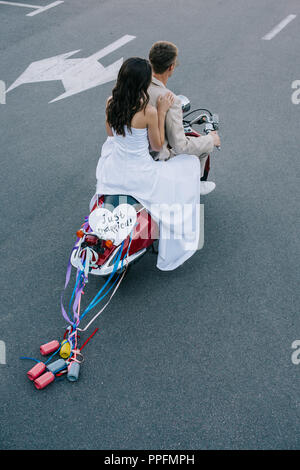 Hochzeit paar reiten Roller mit 'Just Married' Herz Zeichen und bunten Dosen auf Bänder Stockfoto