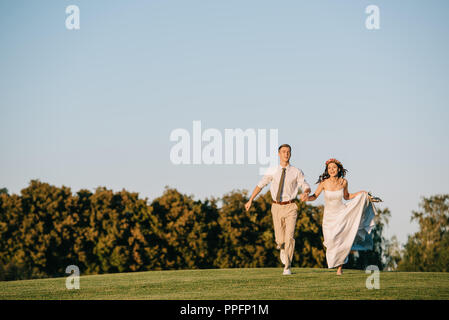 Glückliche junge Hochzeit Paare, die auf der grünen Wiese im Park Stockfoto