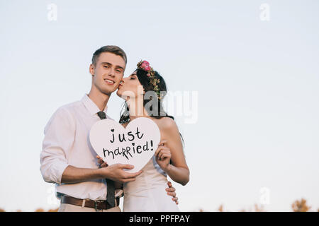 Schöne glückliche junge Hochzeit paar Herzen Holding mit Just married Beschriftung Stockfoto
