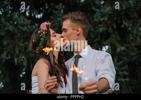 Schöne glückliche junge Hochzeit paar Küssen und halten Wunderkerzen Stockfoto