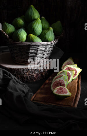 Stillleben mit Feigen in einem Korb auf alten Holztisch. Stockfoto