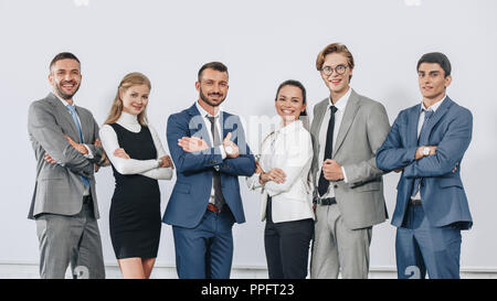 Lächelnd Geschäftsleute mit verschränkten Armen in der Nähe von Bord nach der Ausbildung in der Nabe posing und Kamera Stockfoto