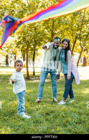 African American Vater verweist auf fliegenden Drachen zu Tochter in Park Stockfoto