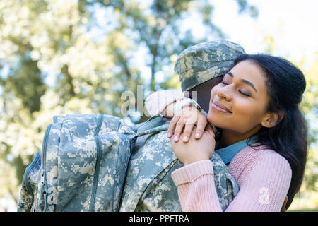 Afrikanische amerikanische Soldaten in Uniform umarmen Freundin im Park Stockfoto