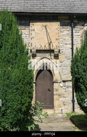 Wand Sonnenuhr aus dem 18. Jahrhundert über einen Eingang zu der Hl. Laurentius Kirche, Eyam, Derbyshire, Großbritannien Stockfoto