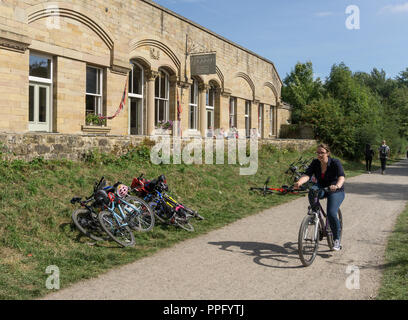 Weibliche Radfahrer auf der Monsal Trail vorbei an den alten Hassop Bahnhof, jetzt ein Café und Buchhandlung; Derbyshire, Großbritannien Stockfoto