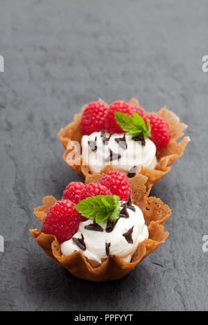 Brandy snap Körbe mit Eis und Beeren auf schwarzen Stein Hintergrund Stockfoto