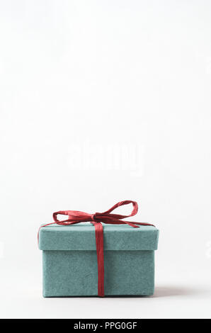 Eine einfache, klare, Türkis Geschenk Box mit Deckel. Geschlossen und mit roten raffia Band gebunden. Kopieren Raum über. Stockfoto