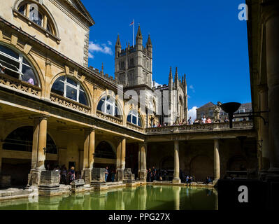 Besucher die Erkundung der historischen römischen Bädern mit Badewanne Abtei überragt, Badewanne, Somerset, England, UK. Stockfoto