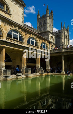 Besucher die Erkundung der historischen römischen Bädern mit Badewanne Abtei überragt, Badewanne, Somerset, England, UK. Stockfoto
