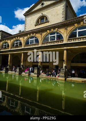 Besucher erkunden und Entspannung durch die große Badewanne des historischen Römischen Bäder, Badewanne, Somerset, England, UK. Stockfoto