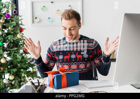 Überrascht Geschäftsmann im Winter Pullover suchen an Weihnachten Geschenkverpackung Stockfoto