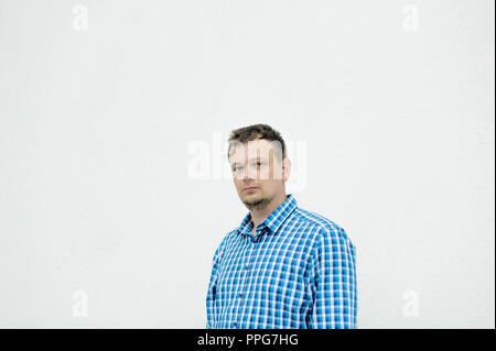 Porträt eines jungen Mannes mit zerzausten Haaren, mit Bart, in einem blau-karierten Hemd Stockfoto