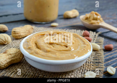 Peanut Butter in eine keramische Schüssel auf einen hölzernen Tisch. Ein traditionelles Produkt der amerikanischen Küche. Stockfoto