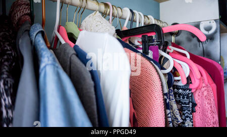Viele bunte Kleidung aufhängen auf rosa Kleiderbügel mit unterschiedlichen Farben und Muster Nahaufnahme Foto. Makro photgraphy Stockfoto