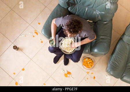 Mann mit Bier und Chips vor dem Fernseher zu Hause Stockfoto