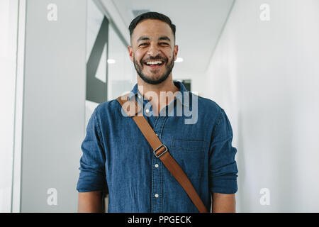 Porträt der glückliche junge Mann im Büro Flur. Mann in Casuals im Büro Flur. Stockfoto