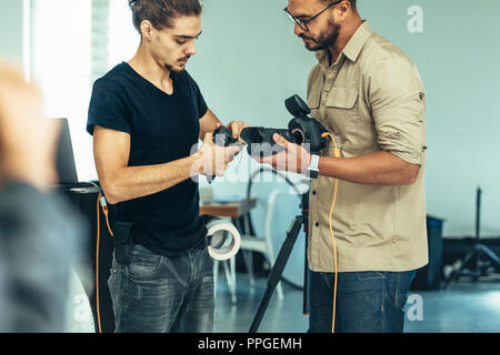 Camera Assistant hilft ein Fotograf in wechselnden Objektiv auf eine DSLR-Kamera während ein Foto schießen. Stockfoto