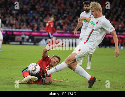 München, Deutschland. 25 Sep, 2018. Bayern München Thomas Mueller (unten) Mias mit der Augsburger Martin Hinteregger während eines Deutschen Bundesligaspiel zwischen Bayern München und FC Augsburg, in München, Deutschland, an Sept. 25, 2018. Das Spiel endete 1-1. Credit: Philippe Ruiz/Xinhua/Alamy leben Nachrichten Stockfoto