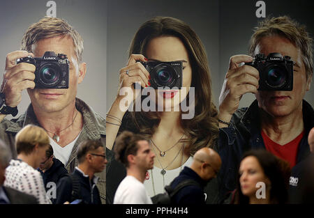 26. September 2018, Nordrhein-Westfalen, Köln: Besucher gehen auf die Messe vor der Plakate. Fotografie Photokina, der größten Messe der Welt, wird in Köln stattfinden, bis 29. September 2018. Foto: Oliver Berg/dpa Stockfoto