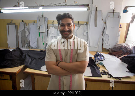 Glücklich auf der Suche nach Maß in seiner Werkstatt stehen mit verschränkten Armen. Stockfoto