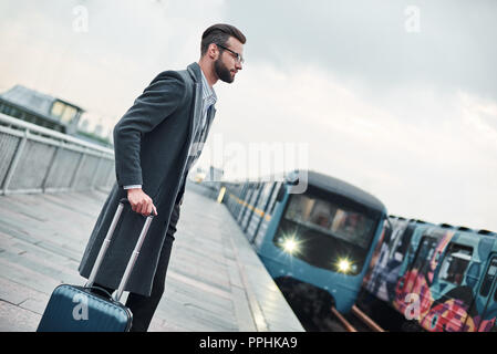 Business Reise. Junge Unternehmer in der Nähe von Bahn mit Gepäck warten auf Zug Stockfoto