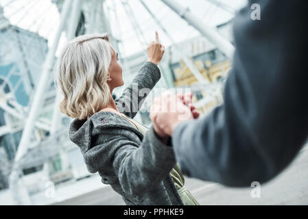 Romantisches date im Freien. Junges Paar gehen mit Entertainment Park halten sich an den Händen Frau Close-up zeigt auf Riesenrad aufgeregt Stockfoto