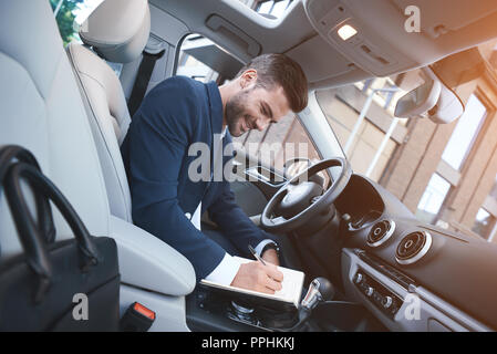 Geschäftsmann schreibt Notizen im Auto, erste Schritte für ein Treffen bereit Stockfoto