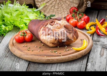 Geräucherter Schinken Hock mit Kräutern und Gewürzen auf Holzplatte. Stockfoto