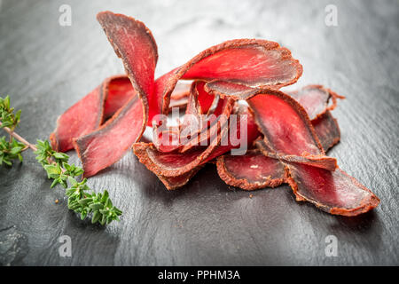 Armenische basturma. Rindfleisch geheilt und Würze. Organische Produkte auf einem Holztisch Stockfoto