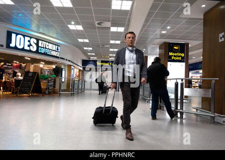 Ein Passagier zu Fuß durch den Flughafen nach der Ankunft am internationalen Flughafen Manchester T1 Ankunftshalle Stockfoto