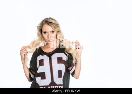 Schöne blonde Frau im American Football Uniform an Kamera isoliert auf weißem suchen Stockfoto