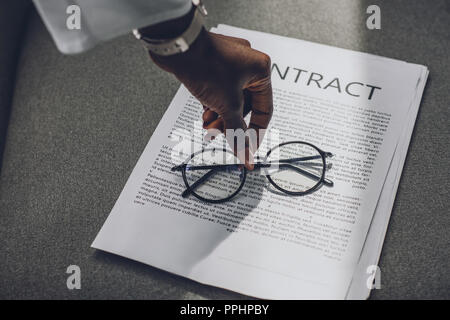 Zugeschnittenes Bild des afrikanischen amerikanischen Geschäftsfrau, Gläser auf Vertrag im Büro Stockfoto